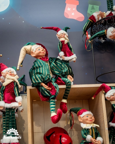 Des elfes décoratifs en tenue de Noël sur des étagères en bois.